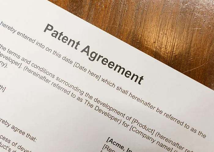 Patent agreement document on wooden table representing jobs that only a person without a soul would do.