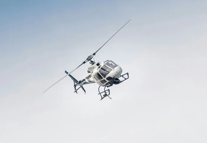 White helicopter flying in the sky, an example of an insane family flex that might make you feel jealous.