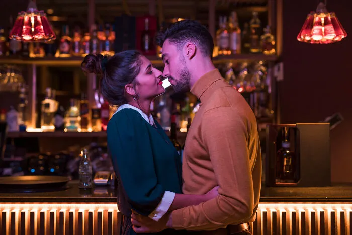 Couple sharing a romantic moment at a bar, illustrating smooth pickup lines and intimate connection in a dimly lit setting.