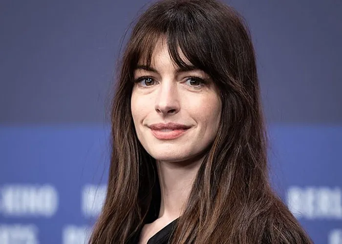 Actress with long brown hair and bangs smiles softly at an event, captured in a candid celebrity encounter moment.