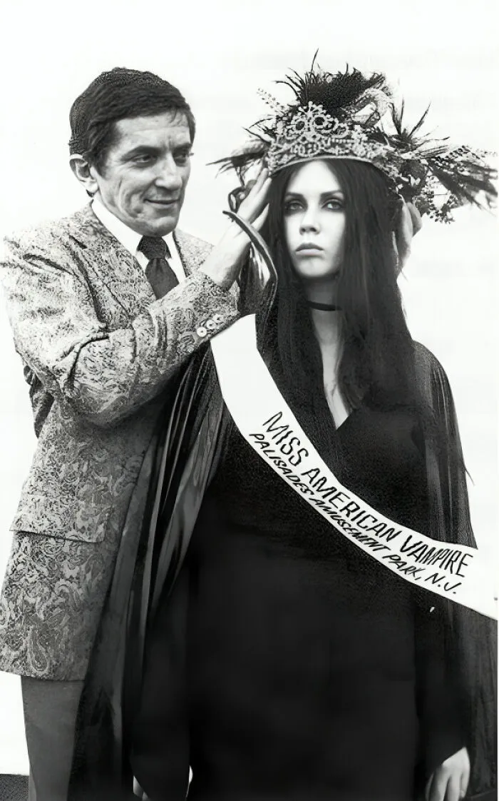Hombre coronando a la ganadora del concurso Miss American Vampire en una foto antigua y con contexto histórico.