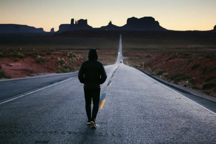 Person walking alone on a long road at dusk with desert landscape, illustrating cool facts about the human body.