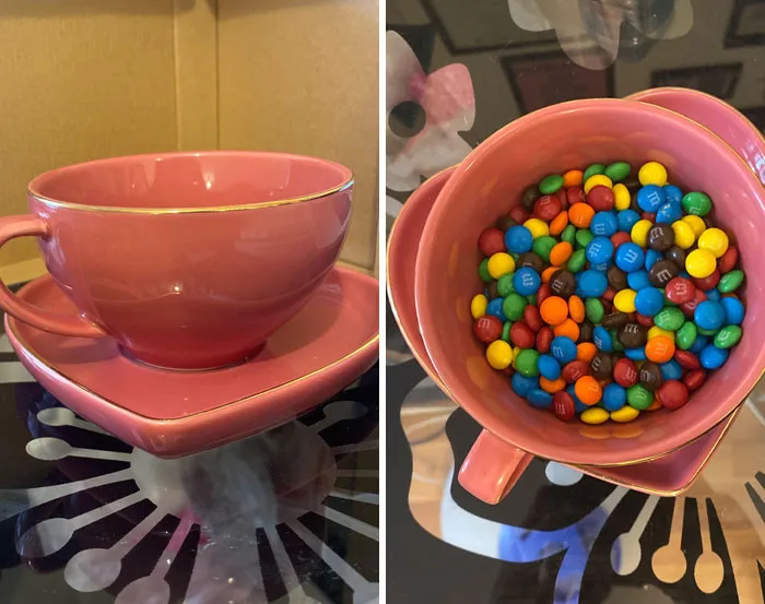 Taza rosa con plato en forma de corazón lleno de dulces de colores mostrando humor ingenioso y creatividad visual.