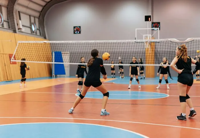 Girls playing volleyball indoors, showcasing human body movement and coordination with focus and agility.