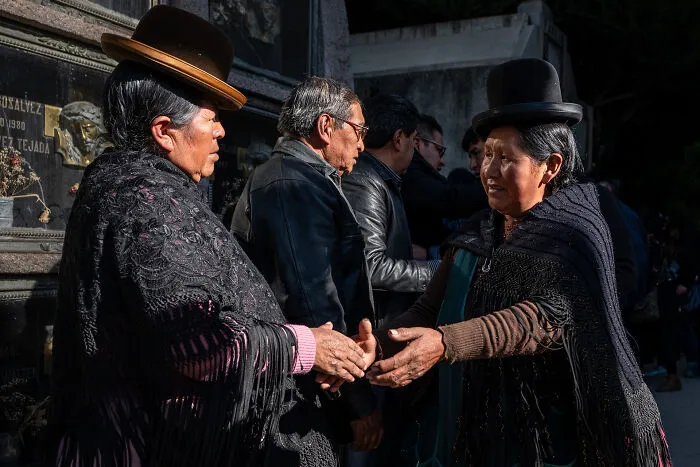 A Mourner Comforts Relatives Of The Deceased At La Paz Cemetery, Bolivia