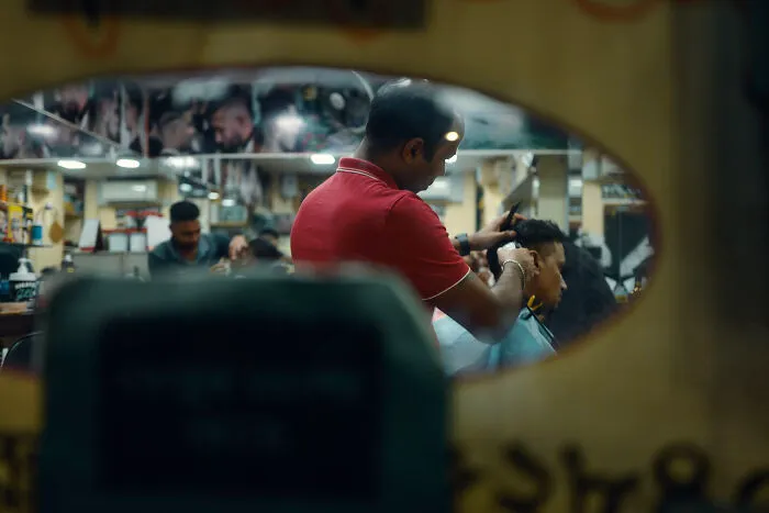 Photographer capturing ordinary moments in a barber shop, creating poetic and cinematic images with natural light and emotion.