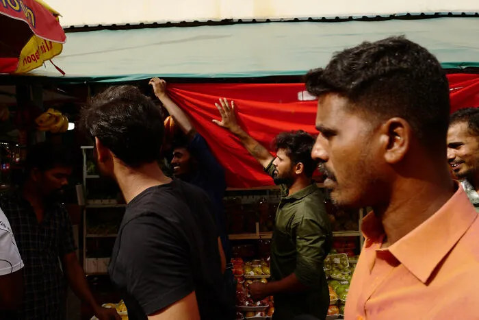 Group of men interacting at a market stall captured in a poetic, cinematic style by a creative photographer.