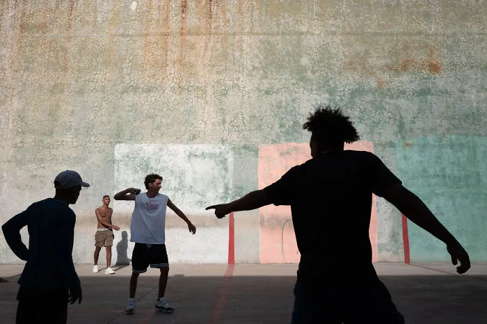 Group of young men playing basketball on an urban court, capturing the beauty of ordinary life in street photography style.