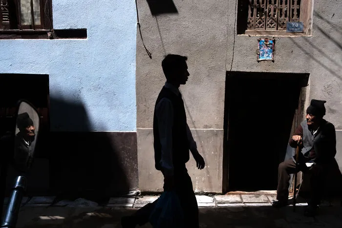 Street photographer captures the beauty of ordinary life with contrasting light and shadows in a quiet urban scene.