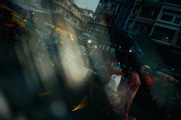 Cinematic image capturing an ordinary street scene with people and market stalls in a poetic, artistic style.