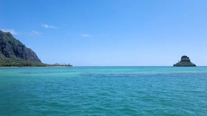 Ocean view with clear blue water and distant island, evoking the serenity of some of the world’s greatest unsolved mysteries.