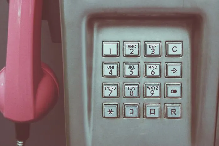 Vintage pink payphone with numeric keypad, illustrating then vs now scenarios in communication technology comparison.