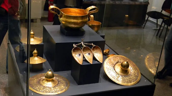Ancient golden artifacts displayed in a glass case, representing some of the world’s greatest unsolved mysteries.
