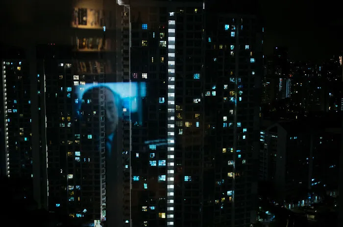Night cityscape with illuminated windows reflecting a cinematic image, showcasing a photographer’s poetic, cinematic style.