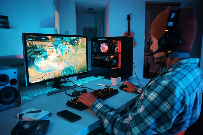 Person gaming on a desktop computer with headset in a dimly lit room, illustrating bizarre reasons for divorce.