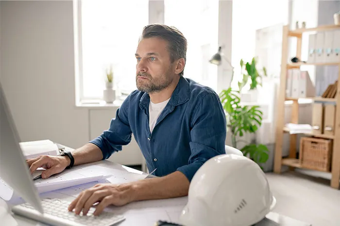 Man in a blue shirt working at a computer, reflecting on bizarre reasons why someone wanted a divorce in an office setting.