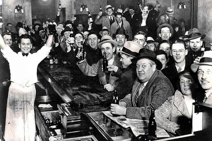 Crowd inside a bar celebrating with drinks, capturing one of the iconic moments in history during Prohibition repeal.