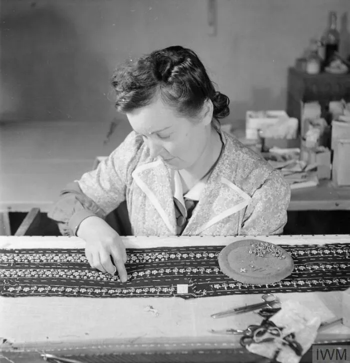 A Skilled Worker Applies By Hand Blue And Gold Studs In Strips To Fabric Which Is To Be Used For A Black Velvet Evening Gown