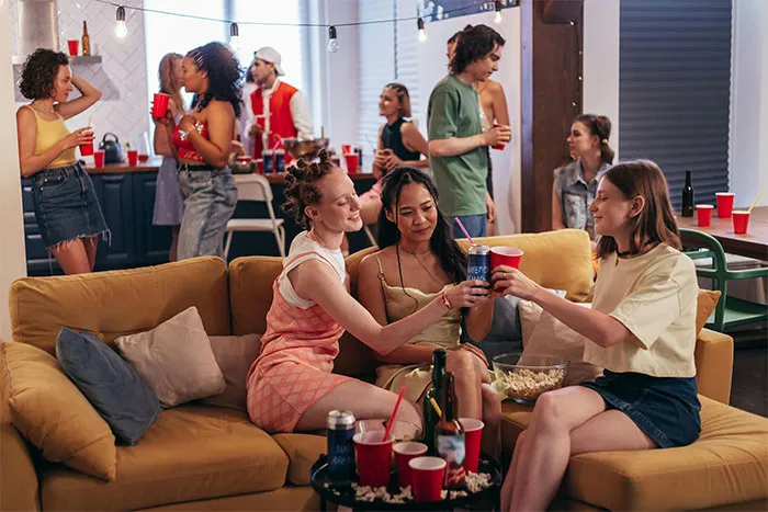 Group of friends at a casual indoor party, enjoying drinks and snacks, sharing moments at a lively gathering.