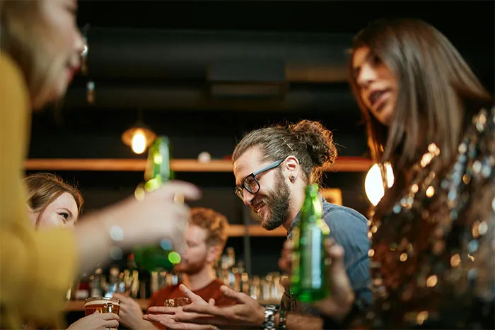 Group of friends socializing and drinking at a bar, sharing stories about the Boston Marathon experience together.