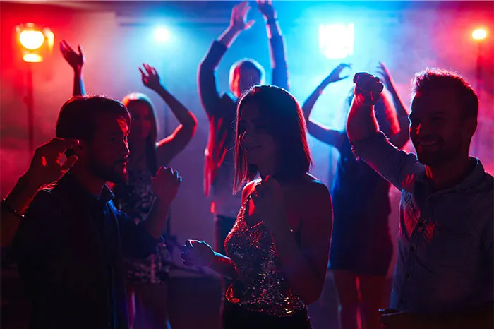 People dancing at a party with colorful lights, capturing the energy and atmosphere of a lively Boston Marathon event celebration.