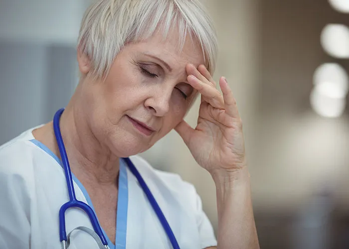 Female doctor with stethoscope, looking stressed and tired, representing doctors who got it wrong in patient care.