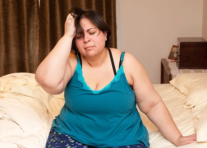 Woman sitting on bed with hand on head, looking distressed, illustrating cases where doctors got diagnosis wrong.