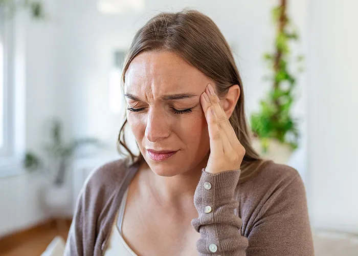 Young woman holding her head in pain, illustrating times doctors got diagnosis wrong and patient suffering.