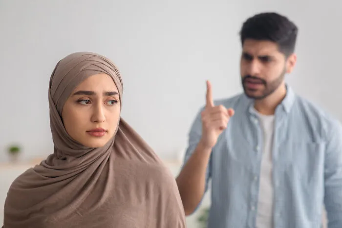 Woman in hijab looking upset while man gestures with finger, illustrating examples of everyday sexism and pressure women face.