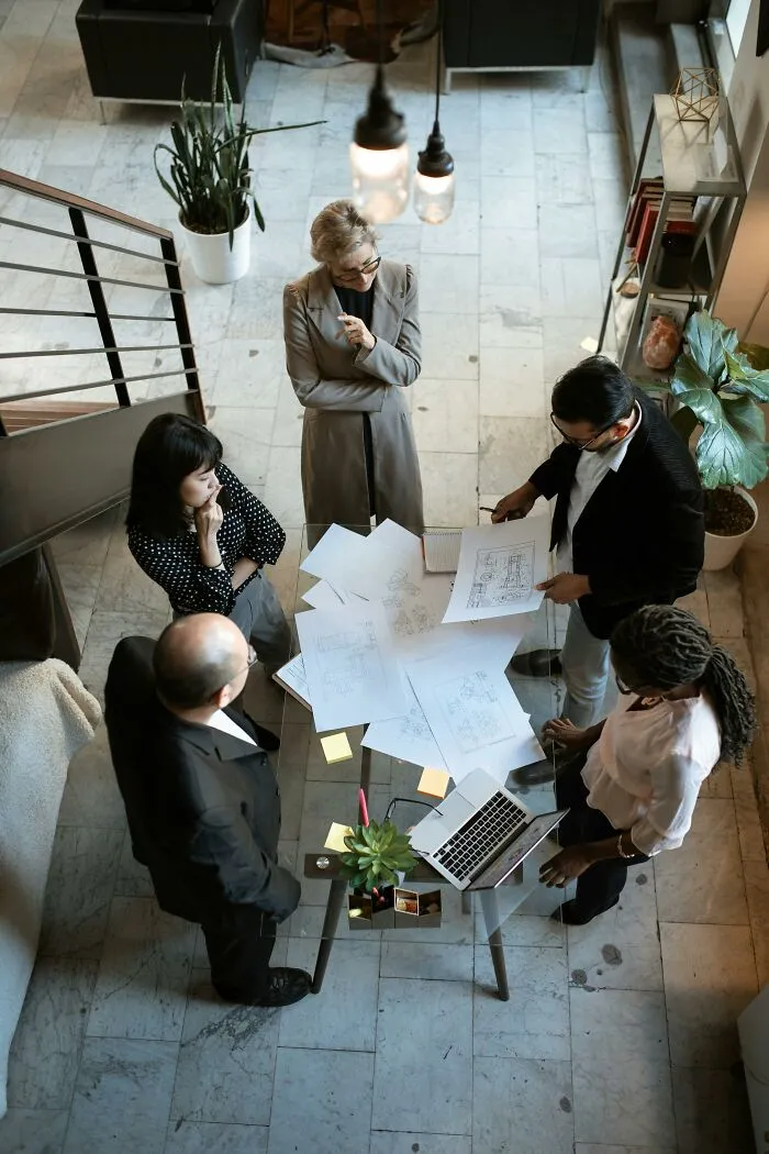 Team meeting with diverse professionals discussing plans and challenging frustratingly out of touch bosses in a modern office setting.
