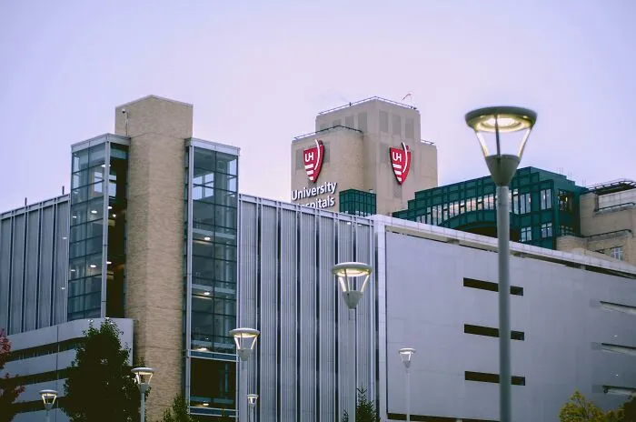 University Hospitals building exterior at dusk with lit street lamps and clear sky in an urban setting.