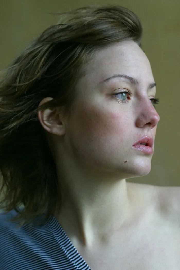 Young woman with tear rolling down her cheek looking away, reflecting on signs of talking to a psychopath.