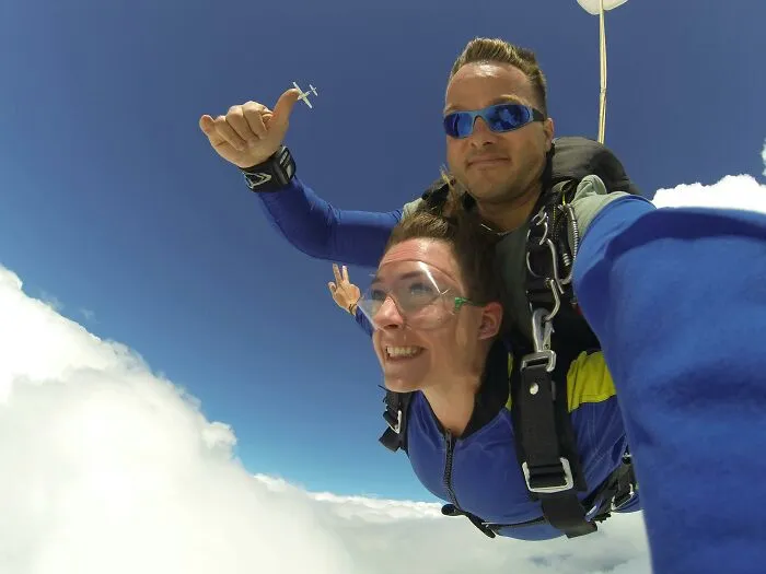 Two people skydiving above clouds on a clear day, illustrating totally safe things that people fear according to netizens.