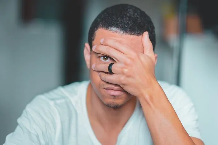 Young man with a black ring partially covering his face, expressing suspicion while talking to a psychopath concept.