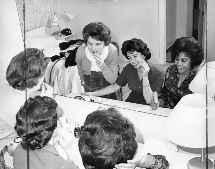 The Women Are Primping In Front Of A Mirror