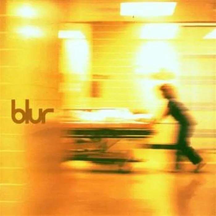 Blur album cover with blurred figure pushing a hospital stretcher in a bright, yellow-toned hallway, evoking eerie space fear themes.