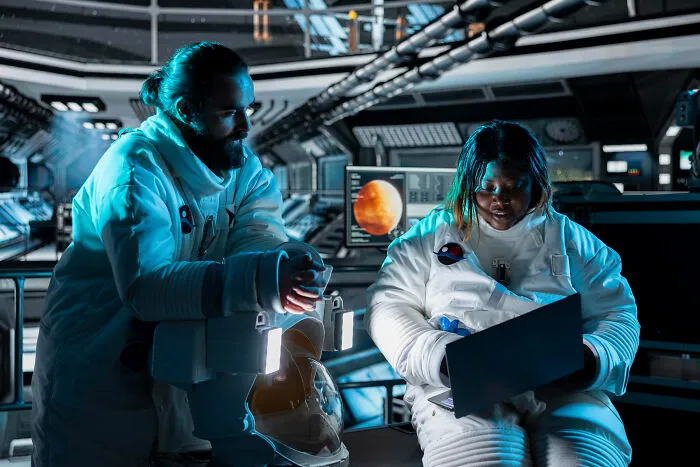 Two astronauts inside a spacecraft reviewing data on a laptop highlighting terrifying space facts and risks.