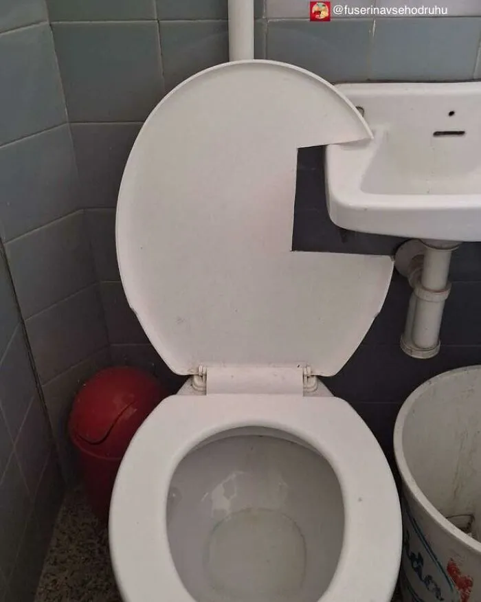 Tapa de inodoro con diseño fallido, cortada para encajar con lavabo, divertido fallo de construcción en baño pequeño.
