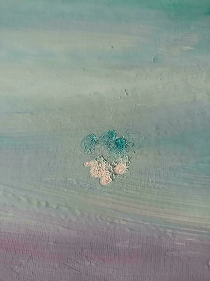 Huella adorable de pata de gato sobre una superficie pintada en tonos pastel mostrando rastros únicos y detallados.