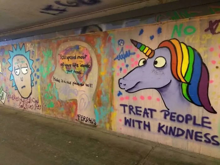 Colorful public property vandalized with graffiti art of a unicorn and motivational messages promoting kindness and positive thinking.
