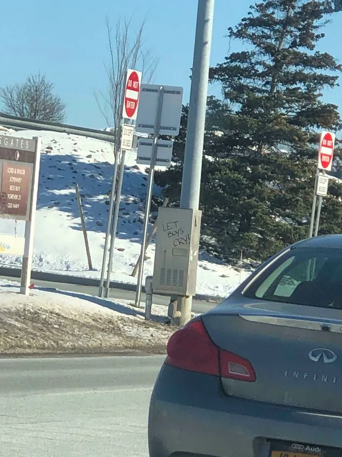 Graffiti on a street utility box reads Let Boys Cry, an example of creative public property vandalism.