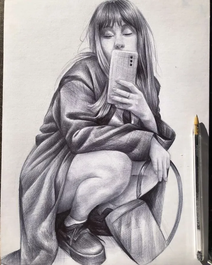 Hyperrealistic ballpoint pen portrait of a woman crouching and holding a phone next to the actual pen used for drawing.