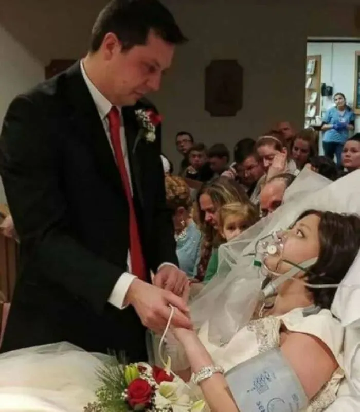 Groom holding hands with bride in hospital bed, capturing a heartwarming story of love and hope against all odds.