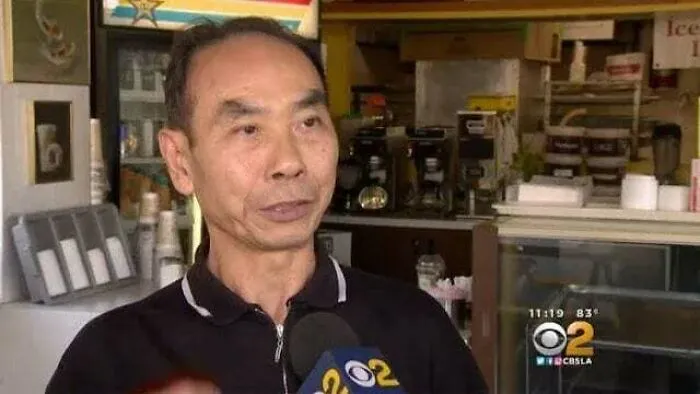 Man speaking in a cafe interviewed by CBS2, sharing heartwarming stories to brighten and cleanse the negativity online.