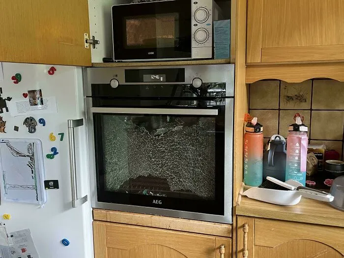Horno con puerta de vidrio rota en cocina, ejemplo de fotos de vacaciones que no salieron como se esperaba.