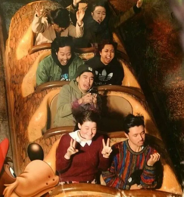 Grupo de personas con gran sentido del humor en atracción de parque de diversiones, capturadas en momento divertido y espontáneo.