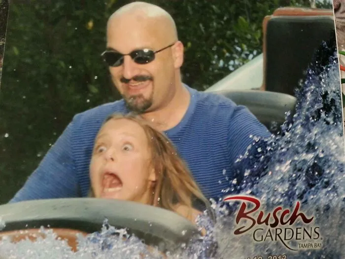 Hombre y niña con gran sentido del humor en parque de diversiones disfrutando un paseo lleno de emociones y risas.