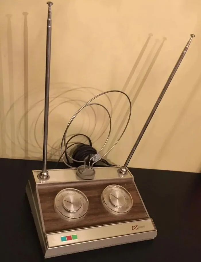Vintage TV antenna with dials and rabbit ears on a table, evoking nostalgia and old age memories.