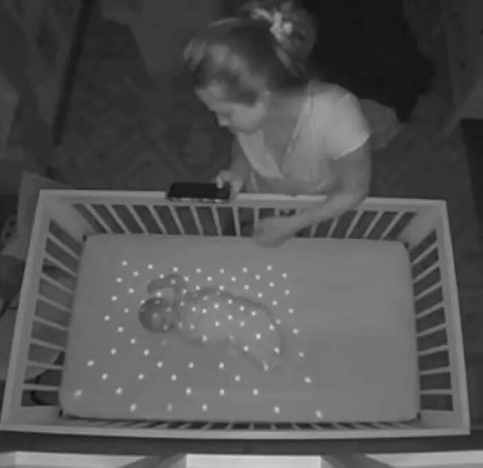 Mujer vigilando bebé en cuna con proyección de luces, ejemplo de objetos que la gente no podía identificar.