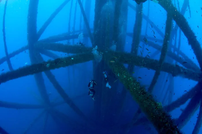 Divers Beneath An Oil Rig